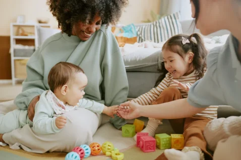 Un petit garçon tient la main d'une petite fille et de sa mère, sous le regard de sa mère