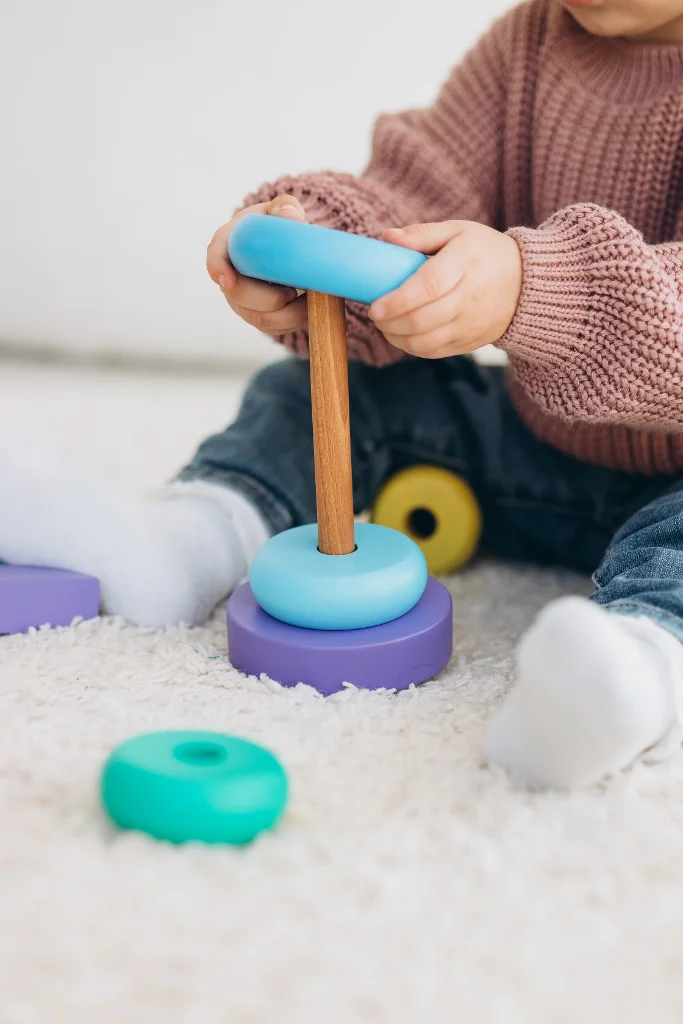 Une adorable petite fille qui joue à la dînette avec des jouets en bois écologiques ; une enfant joyeuse qui coupe des légumes et des fruits avec un couteau jouet ; une enfant qui joue à un jeu éducatif